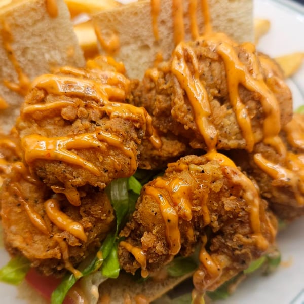 Crispy fried shrimp drizzled with orange sauce, served on a bed of lettuce and bread.