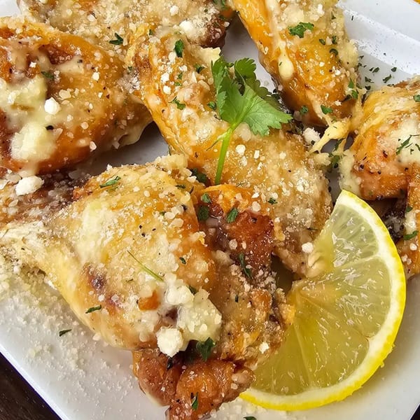 Garlic Parmesan wings from My Brother's Crawfish, garnished with fresh parsley and a lemon wedge.