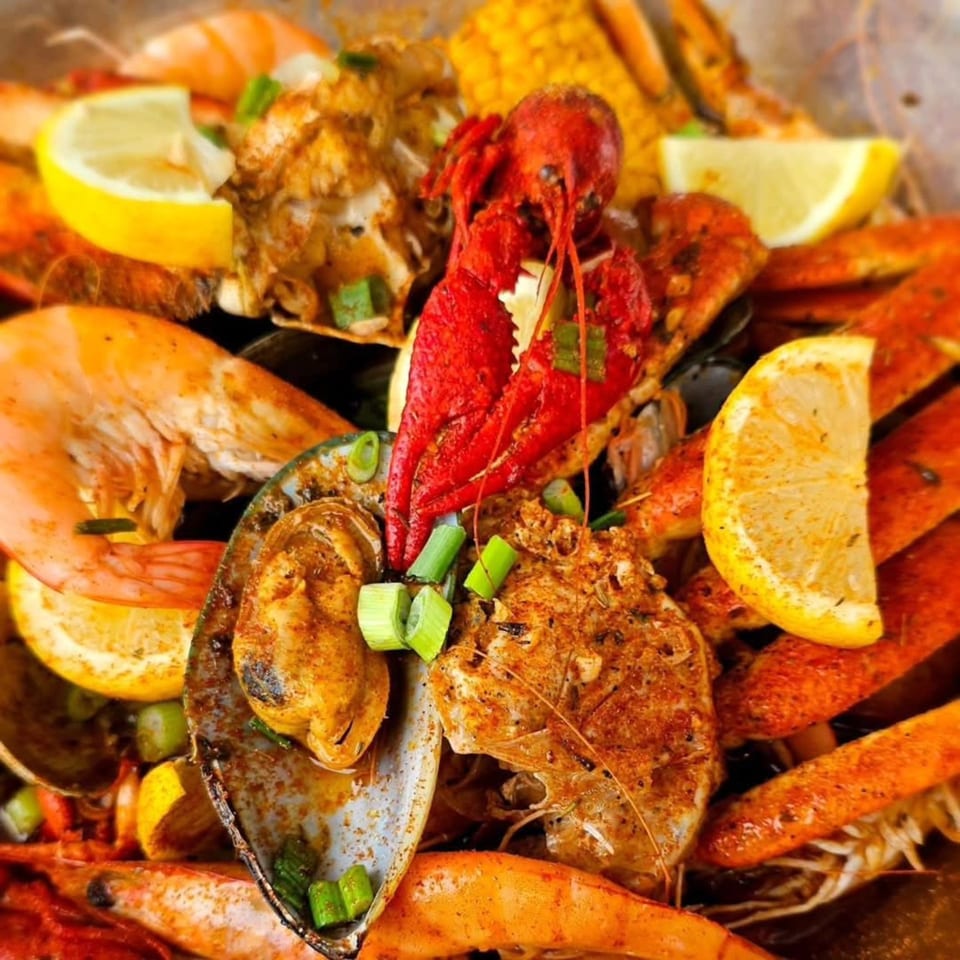 Close-up of My Brother's Crawfish seafood boil with crawfish, shrimp, mussels, corn, and lemon.
